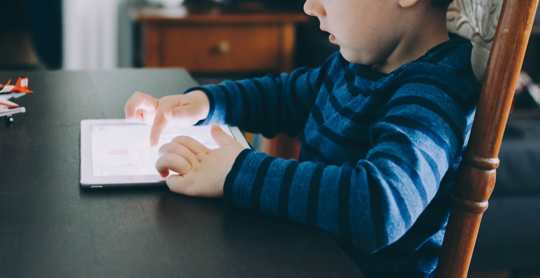 A child working on a tablet at the kitchen table